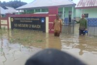 Camat Oba Selatan, Udin Hasan di depan SD Negeri 2 Maidi tergenang air. 
