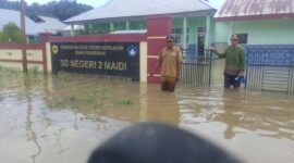 Camat Oba Selatan, Udin Hasan di depan SD Negeri 2 Maidi tergenang air. 