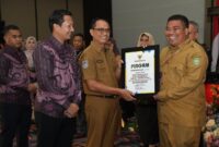 Pj Sekda Malut, Abubakar Abdullah menyerahkan piagam penghargaan kepada Kepala Disnakertrans Malut, Marwan Polosiri. 