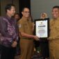 Pj Sekda Malut, Abubakar Abdullah menyerahkan piagam penghargaan kepada Kepala Disnakertrans Malut, Marwan Polosiri. 