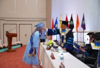 Toga biru muda ala wisudawan Unibrah, terlihat Rektor Sarbaini A Karim memindahkan tali toga. 