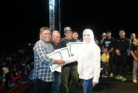 Bupati Sula, Fifian Adeningsi Mus memberi piagam penghargaan kepada Penjabat Kepala Desa Waitulia, Ridwan Buamona. (Dokumentasi: Diskomdigi)